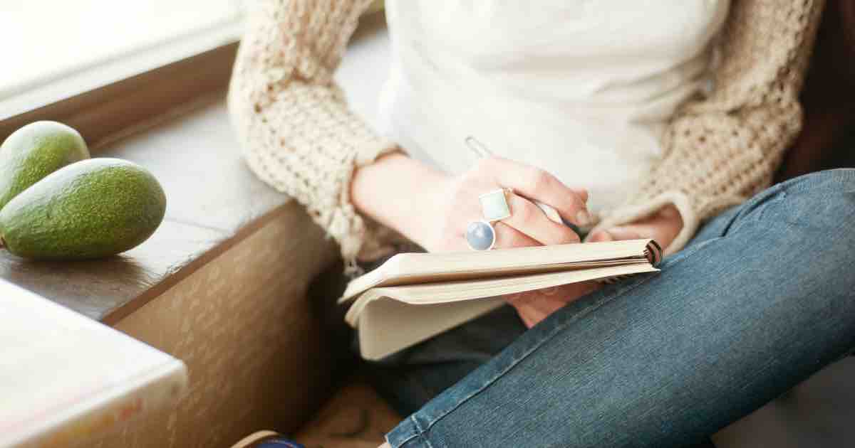 young woman journaling to enhance creative writing and happiness